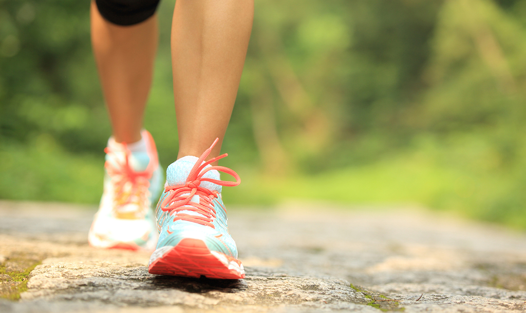 Close-up of a person walking in running shoes on a sunlit path