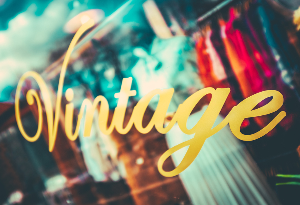 Vintage lettering on a shop window with colourful second-hand clothing behind it